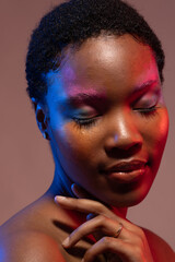 African american woman with short hair and colourful make up touching shoulder with eyes closed