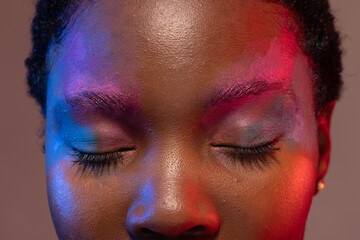 African american woman with short hair and colourful make up with eyes closed