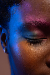 Close up of african american woman with short hair and colourful make up with eye closed