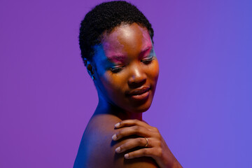 African american woman with short hair and colourful make up looking down with hand on shoulder