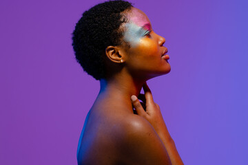 African american woman with short hair and colourful make up touching neck