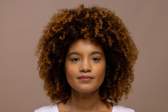 Biracial woman with curly hair looking straight to camera