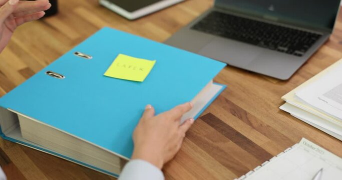 Secretary sticks sticker with inscription later on business folder with documents. Work with documents