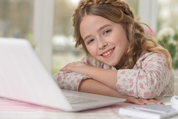 Cute and happy little girl children using laptop computer