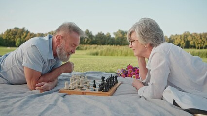 Retired man and woman competing in game of chess outside - Powered by Adobe