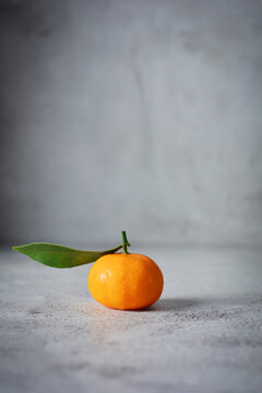 Fresh single orange fruits with one leaf. mandarin orange on grey and texture background 