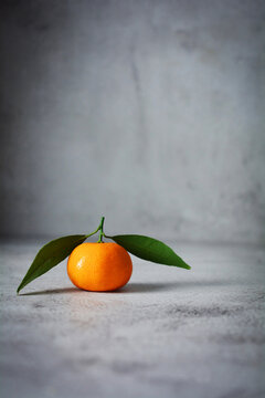 Fresh orange fruits with two leaves. mandarin orange on grey and texture background 