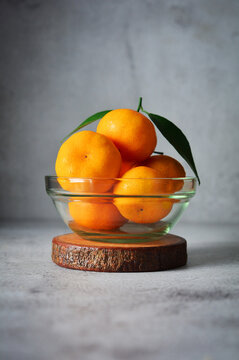 bunch of fresh orange fruits in a glass bowl. mandarin orange on grey and texture background 