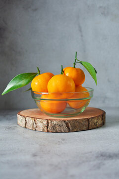 bunch of fresh orange fruits in a glass bowl. mandarin orange on grey and texture background 