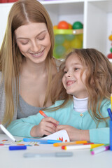 Preschool education concept. Professional woman teacher exercising with little pupil, cute boy reading English letters and words at classroom