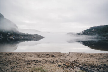 Mountains in Norway. Lake, beach and mountains near Preikestolen. With fog a fairytale picture.
