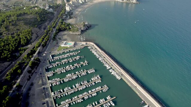 Aerial revealing drone view of Oropesa del Mar and its sports port among clear blue sea water, Spain