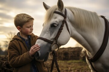 Obraz premium The boy strokes his white horse. Growing up on a farm with animals, slow living concept. 