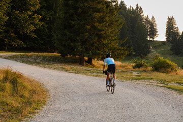 Obraz premium Professional athlete cyclist ride carbon gravel bike with beautiful mountain view at sunset. Cycling exploration adventure.Cyclist practicing on gravel road.Man cycling in the nature.Bucegi Mountains