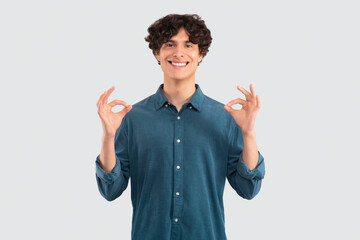 Guy in casual showing okay gesture with both hands, studio