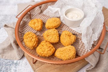 Air fried breaded chicken nuggets in a basket with dip and ready to serve