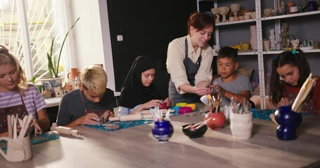 Teacher shows student technique of modeling clay element