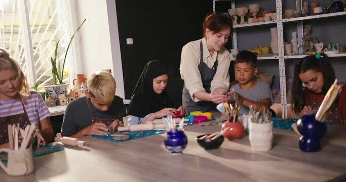 Teacher shows student technique of modeling clay element