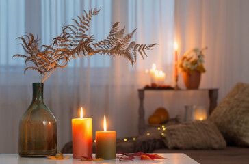 Obraz na płótnie Canvas burning candles with autumn decor on white table at home