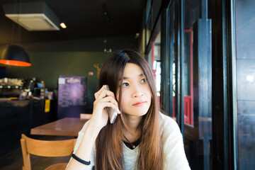 Asian beautiful women talking on smart phone while sitting in cafe