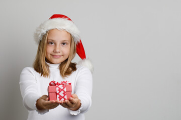 Cute happy child Santa giving red Xmas gift on white studio wall background