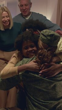 Vertical shot of man in military uniform hugging his parents, wife and son when returning from army