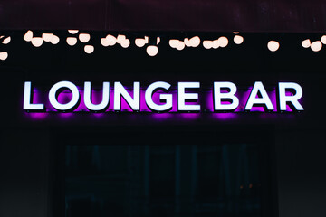 Neon sign on a black background, the inscription Lounge bar with purple light