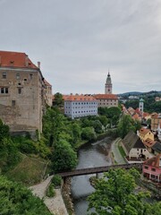 Czech Krumlov, (Cesky Krumlov), Czech Republic. Wooden bridge over river Vltava. Vintage picturesque old town with colorful houses and chapel of church. Rose flowers on bank. 
