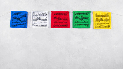 Colorful Tibetan buddhist prayer flags with mantras by Nepal on a grey background, copy space, top view. Tibetan prayer flags have five colors representing the elements or energies in nature