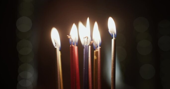 The child blows out the candles on the birthday cake. The face of a child in the dark behind the candles