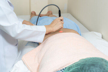 Physiotherapist close up helping woman using special tools shoot the light on his back