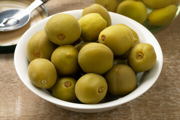 Bowl with whole homemade pickled unripe green almonds close up