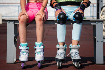 schoolgirls are sitting on a bench after roller skating. girls in protective equipment knee pads...