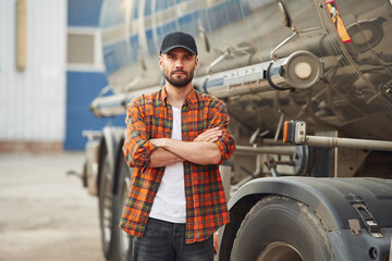 Arms crossed, standing. Young truck driver in casual clothes