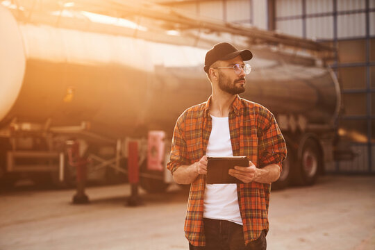 Digital tablet in hands. Young truck driver in casual clothes