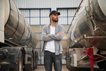 Between two vehicles. Young truck driver in casual clothes