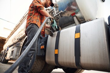 Naklejka premium Young truck driver in casual clothes is refueling the vehicle