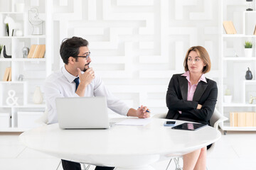 Two concentrated business people working at the desk on laptop in the office	