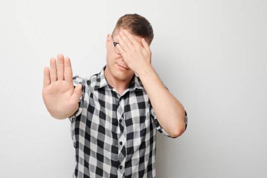 Portrait of frustrated man with face palm making stop gesture with hand isolated on white studio background.