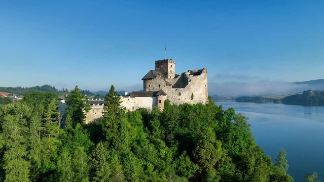 Poland. Medieval Castle in Niedzica, 14th century (upper castle), Artificial Czorsztyn dam lake. Aerial panning video in the morning in sunrise light. Ruin of Czorsztyn castle in the background