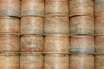 Stacked round yellow hay bales tightly bound in red, white and blue plastic threading in the italian village of Santo Stefano.
