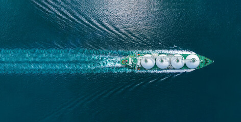 Aerial top view LNG Tanker ship (Liquified Natural Gas) with contrail in the ocean sea ship carrying container and running for export from container international port to custom ocean 