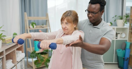 Physiotherapy, arms and senior woman with black man and dumbbell for body assessment. Physical...