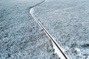 Fotobehang top view of a landscape road in perspective in a winter forest. pine forest covered with snow © metelevan