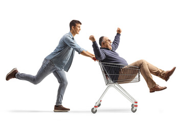 Grandson pushing a mature man seated inside a shopping cart