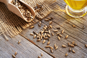 Milk thistle seeds spilled on a table, with milk thistle oil in the background