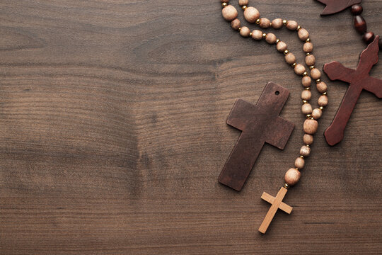 Three Christian crosses on the brown table. Flat lay photo of three crosses on wooden background with copy space.