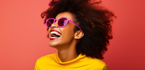 laughing young black woman with cool sunglasses in front of a red background