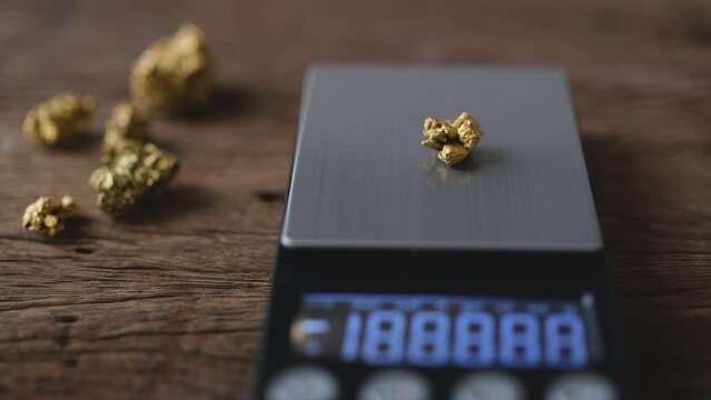 man's hand is weighing a piece of pure gold on a scale