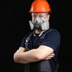 A man wearing a helmet, respirator and goggles on a black background - obrazy, fototapety, plakaty